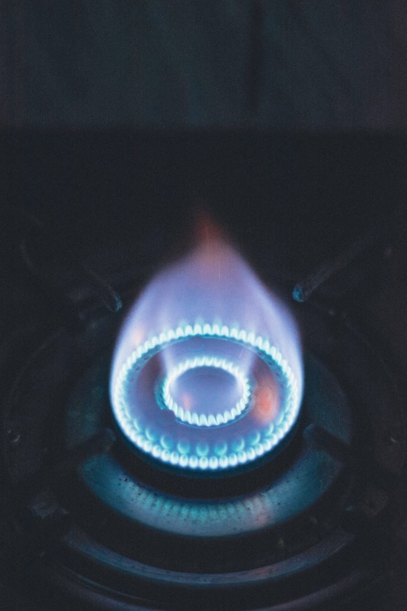 A blue gas flame on a burner in a dark kitchen