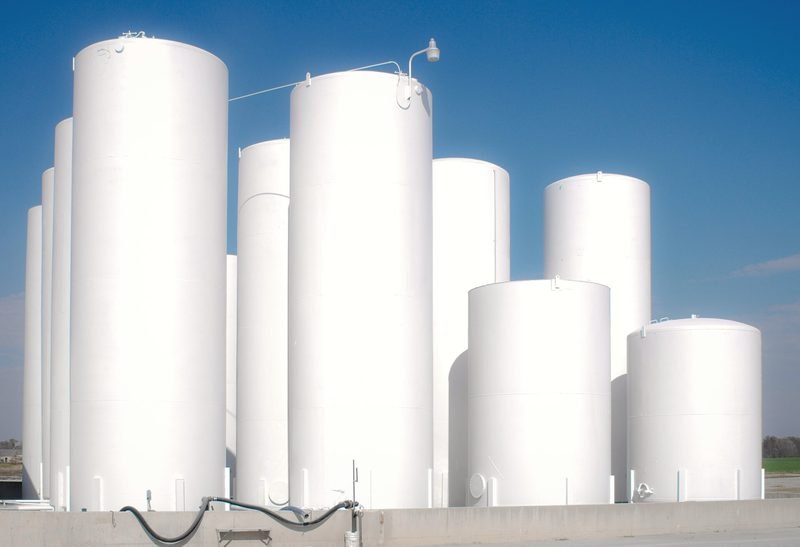 A row of white vertical storage tanks of different heights